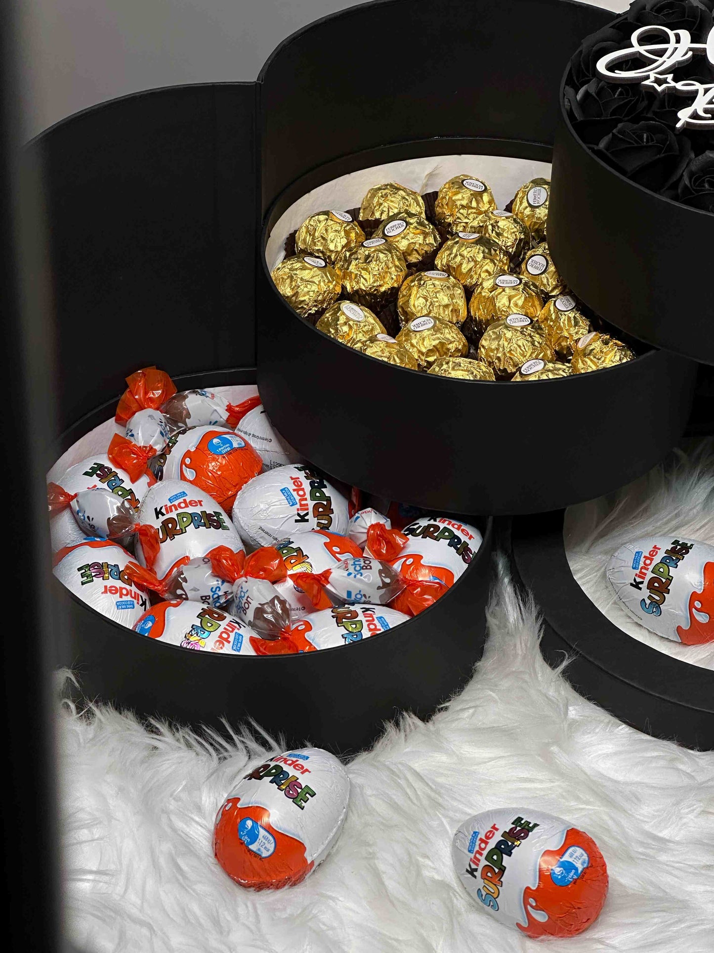 Close-up of the Ferrero Rocher chocolates and Kinder treats from the three-tiered black gift box, highlighting the delicious assortment of sweets.