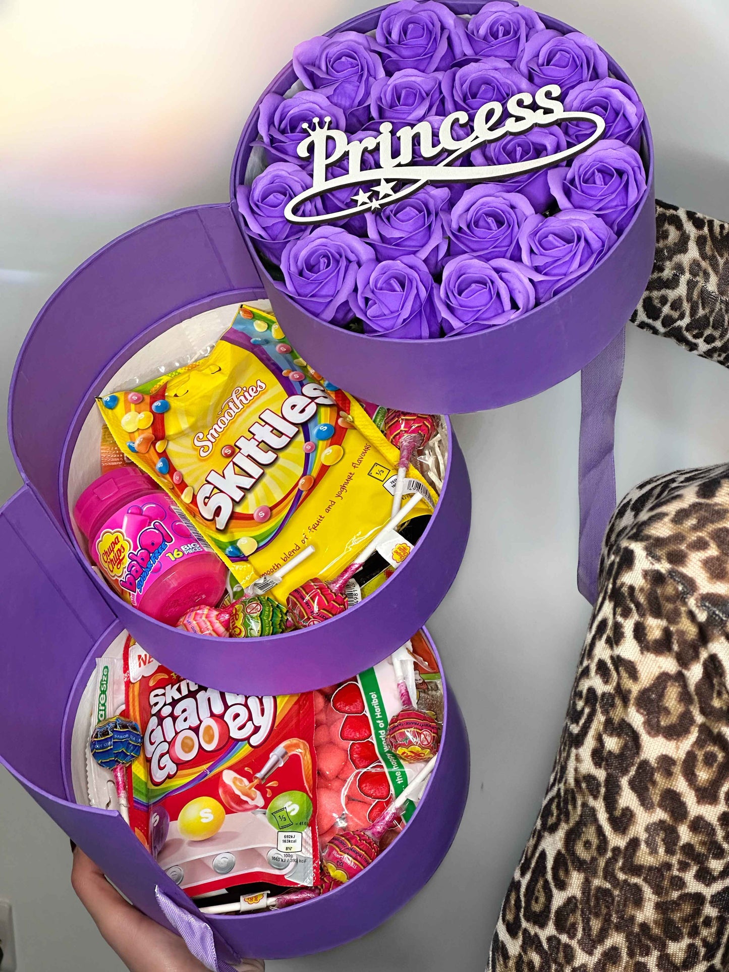 Side view of the three-tiered purple gift box showcasing soap roses, Haribo Strawberry Softies, and Rainbow Strips Zing.